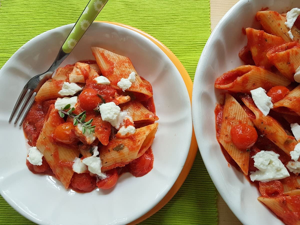 Penne alla pizzaiola topped with cheese.