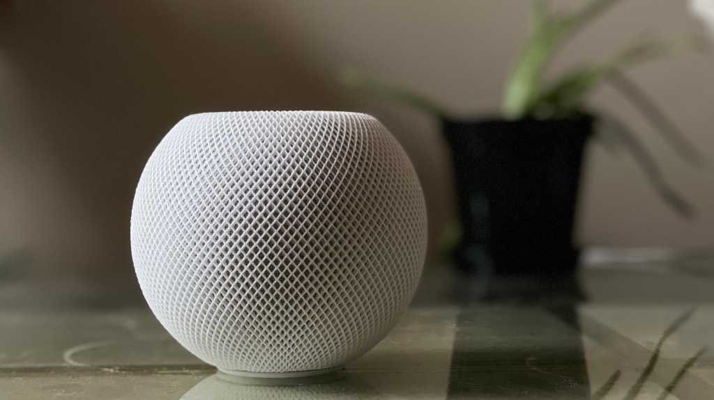 HomePod mini in white on a table next to a plant