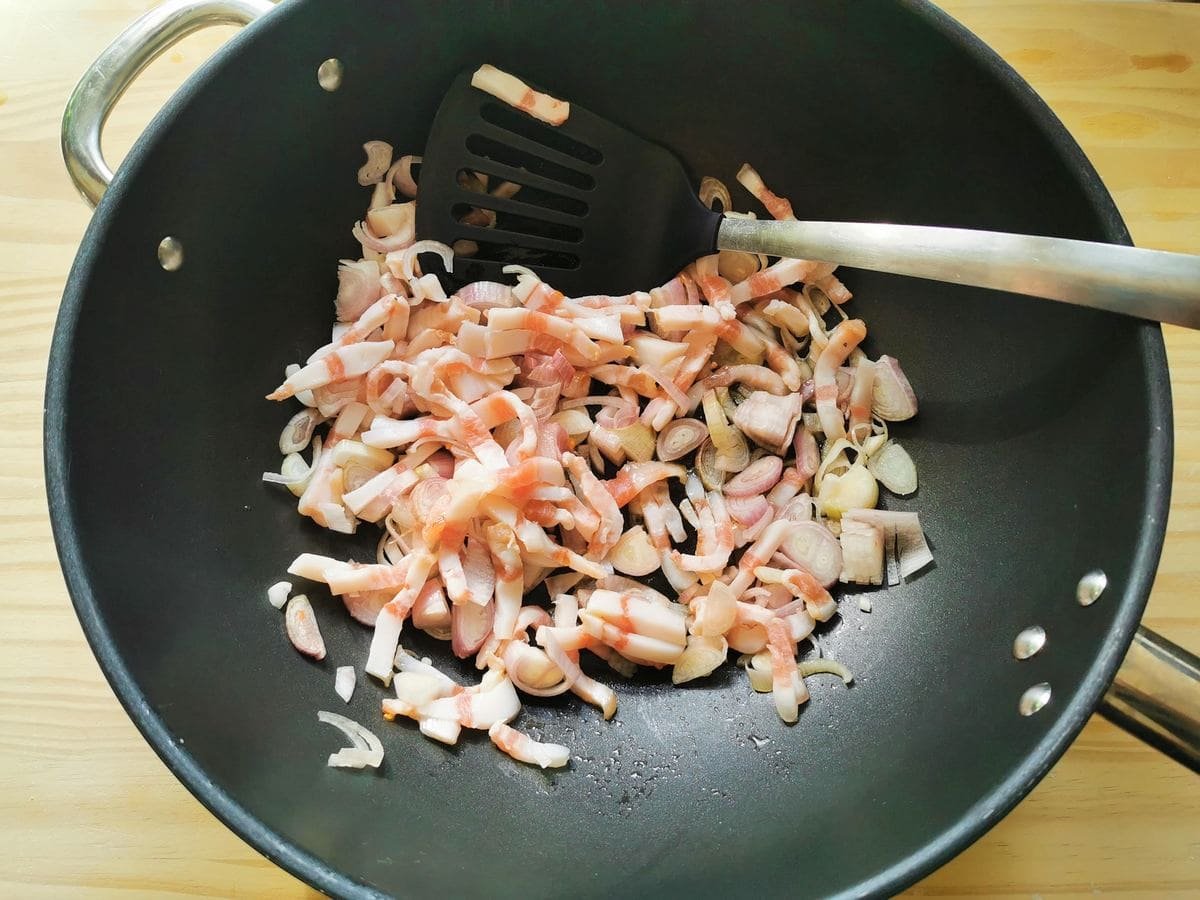 Shallots and guancial in deep frying pan.