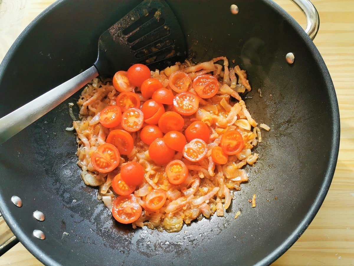 Half -cherry tomatoes in deep frying pan with shallots and guancial.