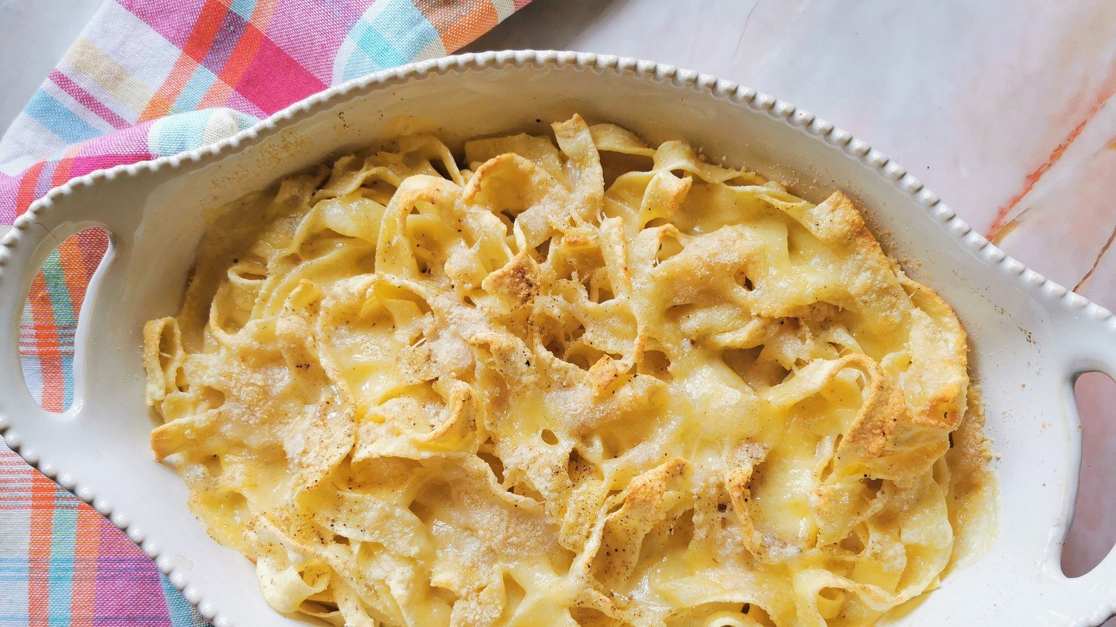 Ready to serve baked tagliatelle in a white oval oven bowl.