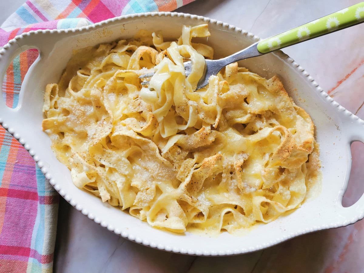 Clear oven baked tagliatelle with fontina cheese in white oval oven bowl.