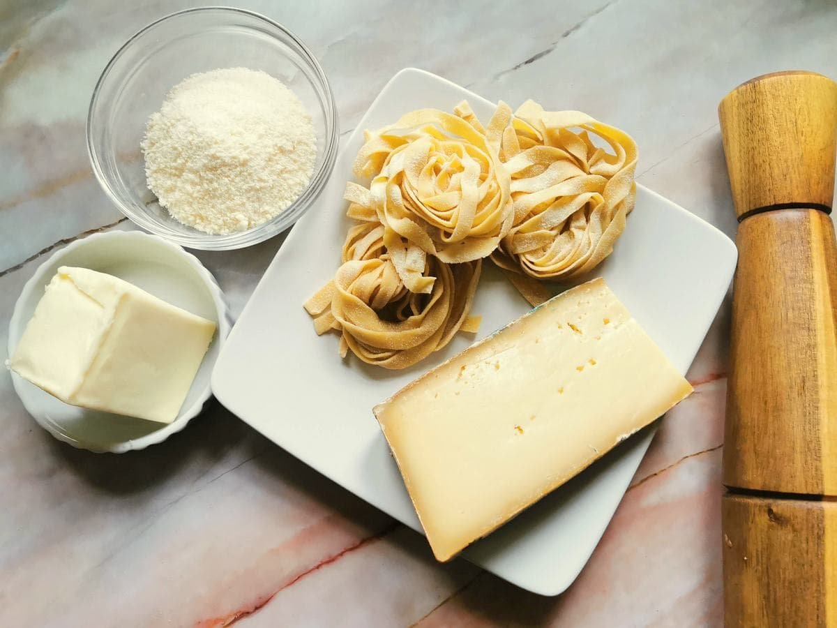 Ingredients for oven baked tagliatelle with fontina cheese on marble work top.