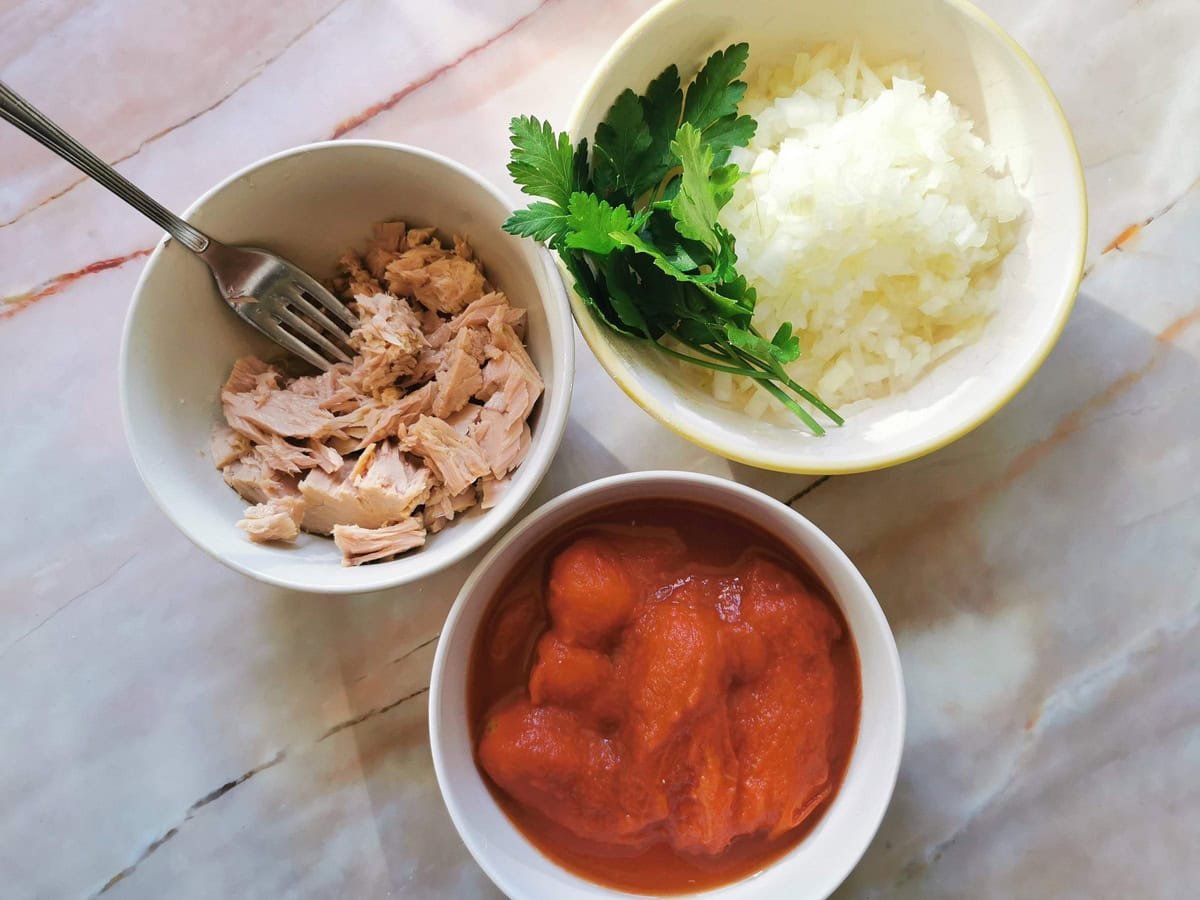 Prepared ingredients for tuna bolognese in white bowls.