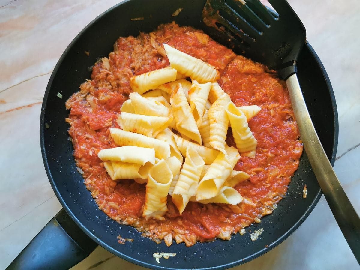 Boiled homemade garganelli in frying pan with tuna bolognese sauce.