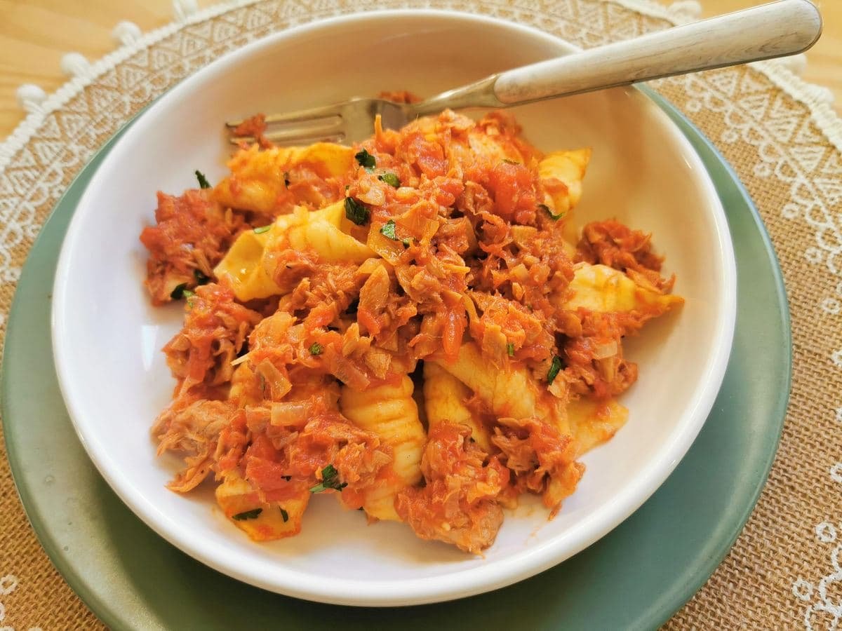 Garganelli pasta with tunbolognese in white bowl.