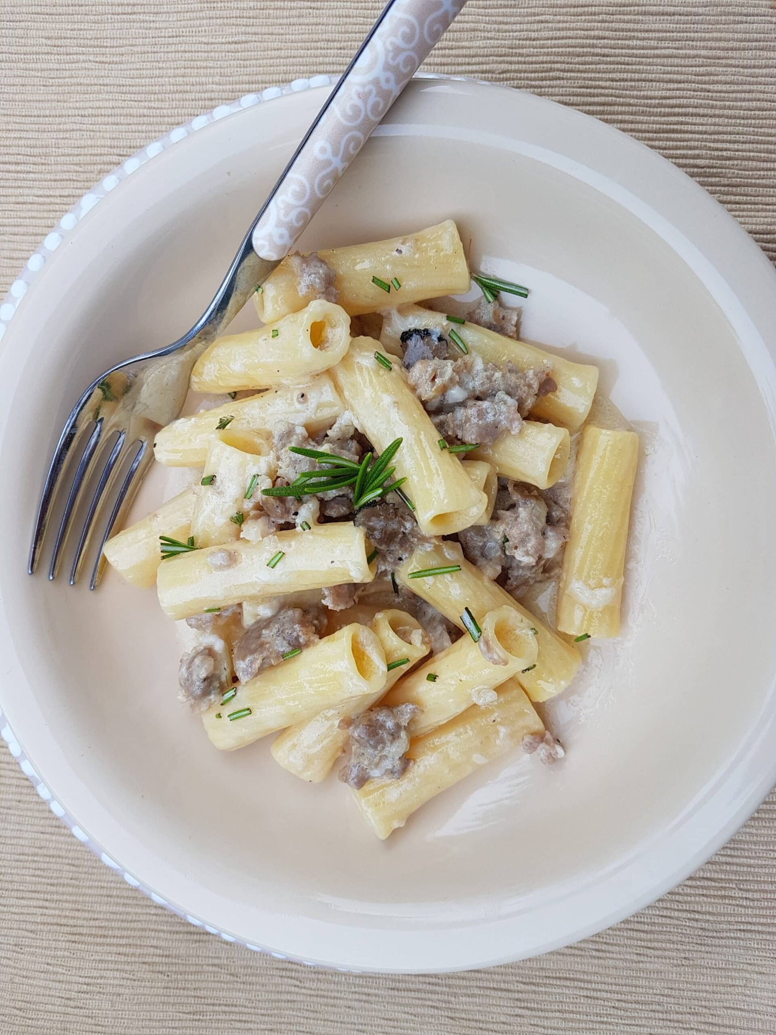 Pasta alla norcina decorated with rosemary.