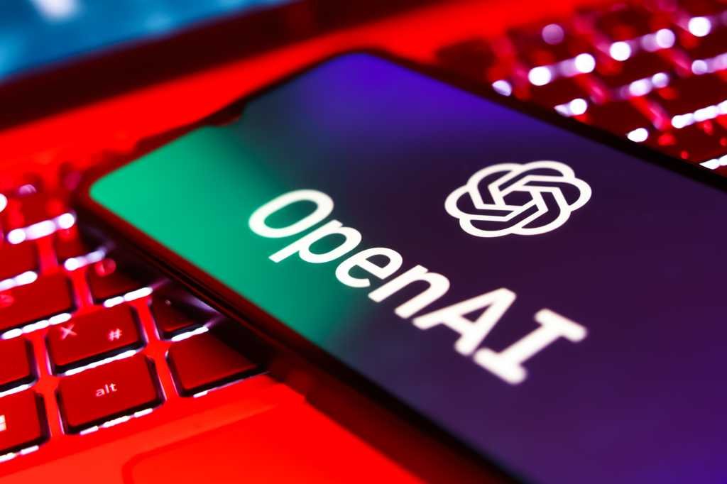 OpenAI logo on a phone screen on top of an open laptop keyboard