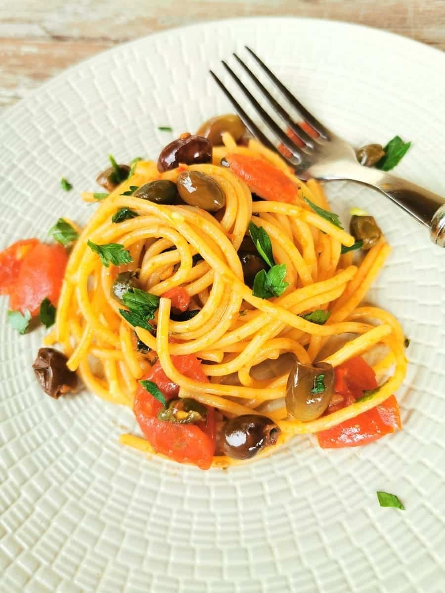 Spaghetti Alla Puttanesca is served on a kitchen table.