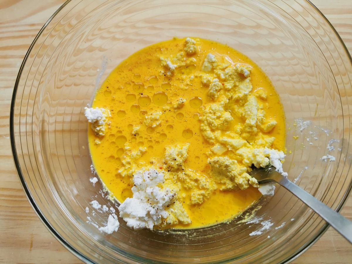 Safran and milk added to ricotta and olive oil in the glass bowl.